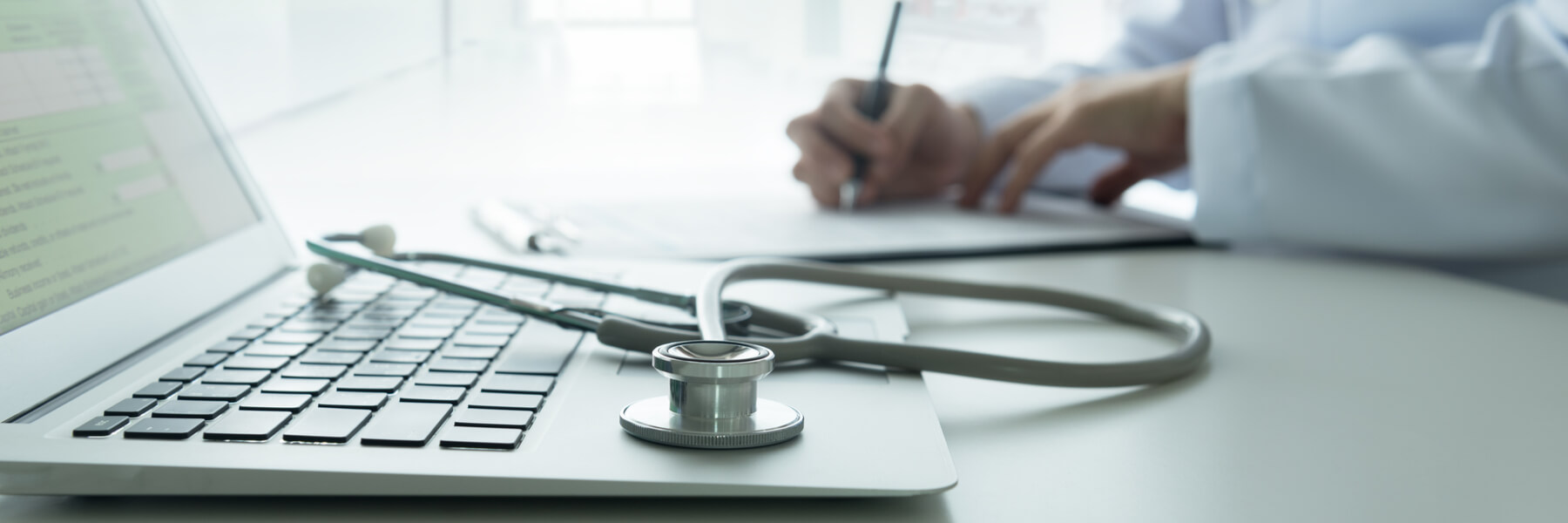 Computer with stethoscope and doctor in background, healthcare industry concept for managed services