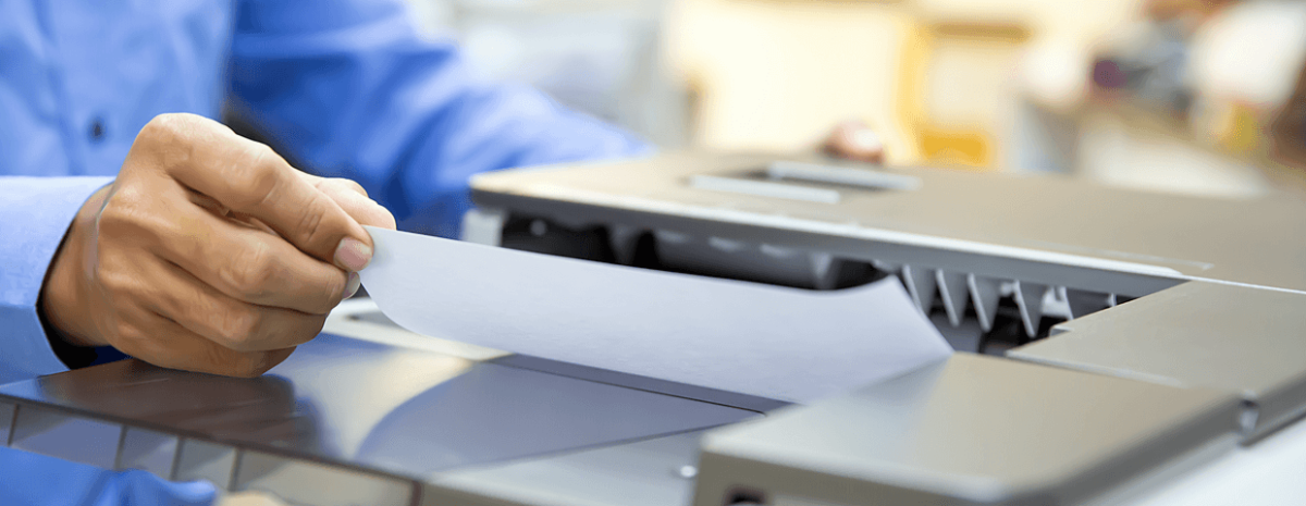 close up of a businessman placing or removing paper from an office copier output tray