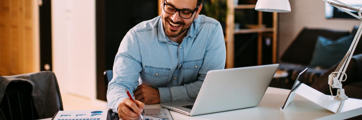 Young business man working at home with laptop and papers on desk