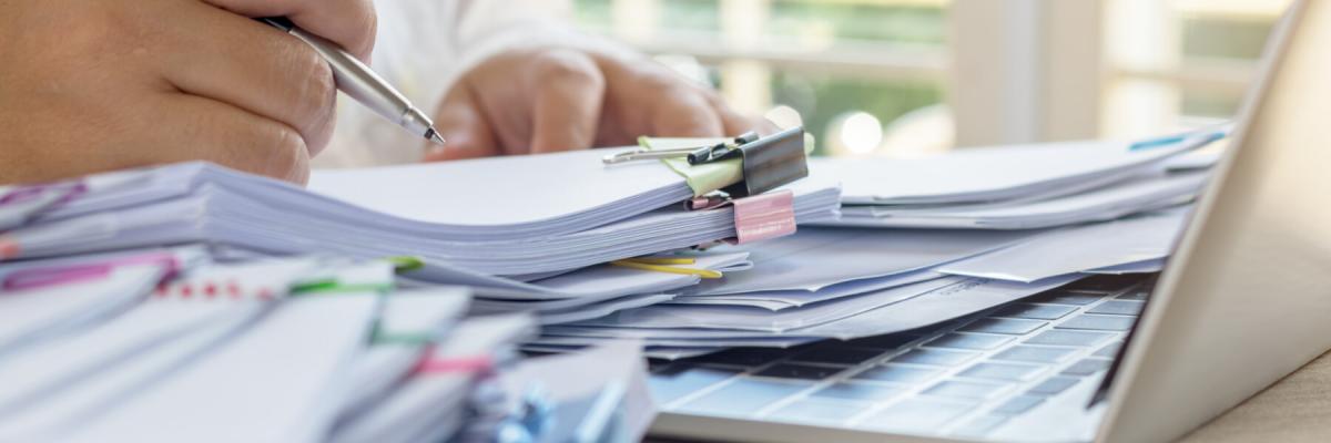 Unfinished paperwork stacked in archive with color paper clips