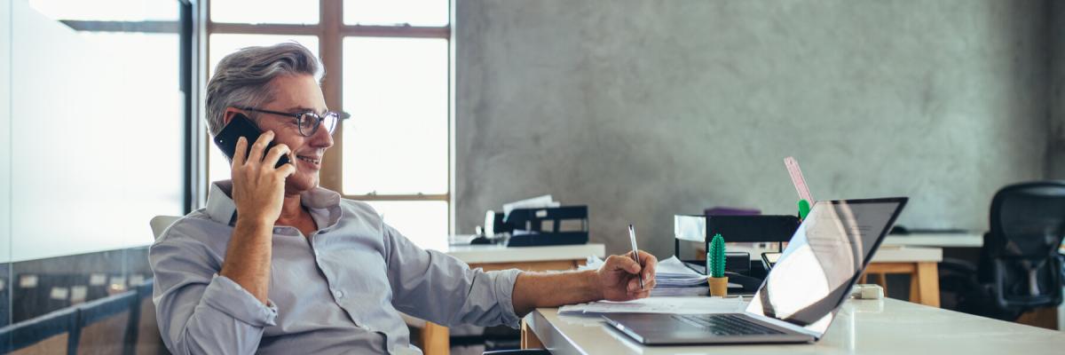 Male business professional in office talking on cell phone.