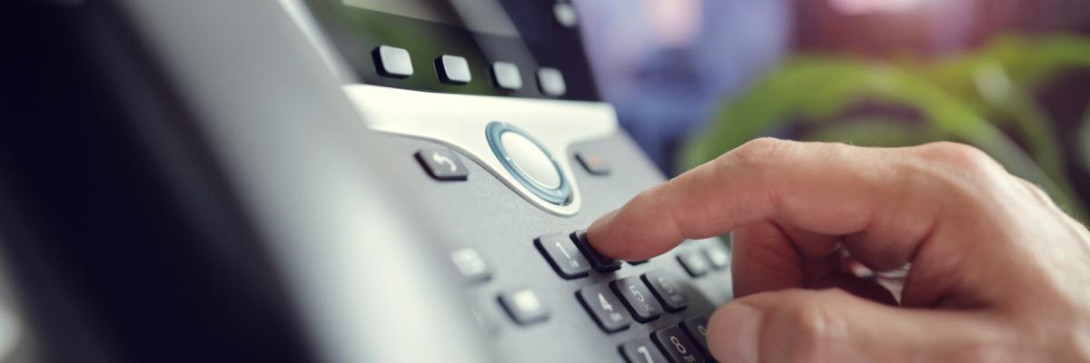 Man punching a phone number into work phone