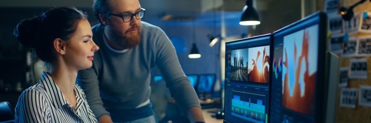 two workers collaborating on two screen setup